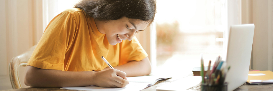 menina estudando ead engenharia elétrica no computador e fazendo anotações.