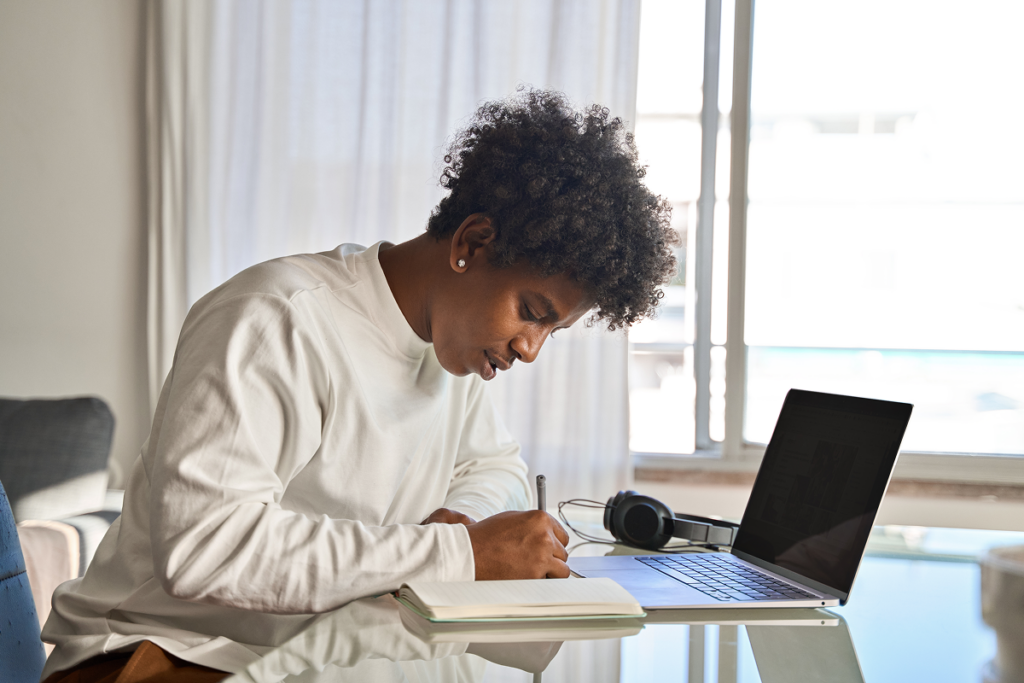 Jovem estudando para o enem e escrevendo em um caderno.