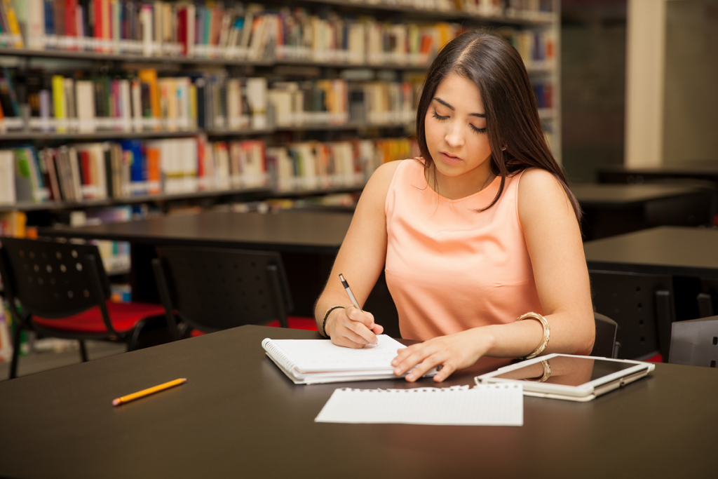 Mulher jovem estudando em biblioteca.