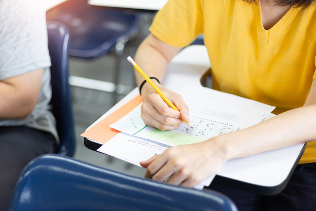 Menina fazendo prova em sala de aula. Redação do enem.