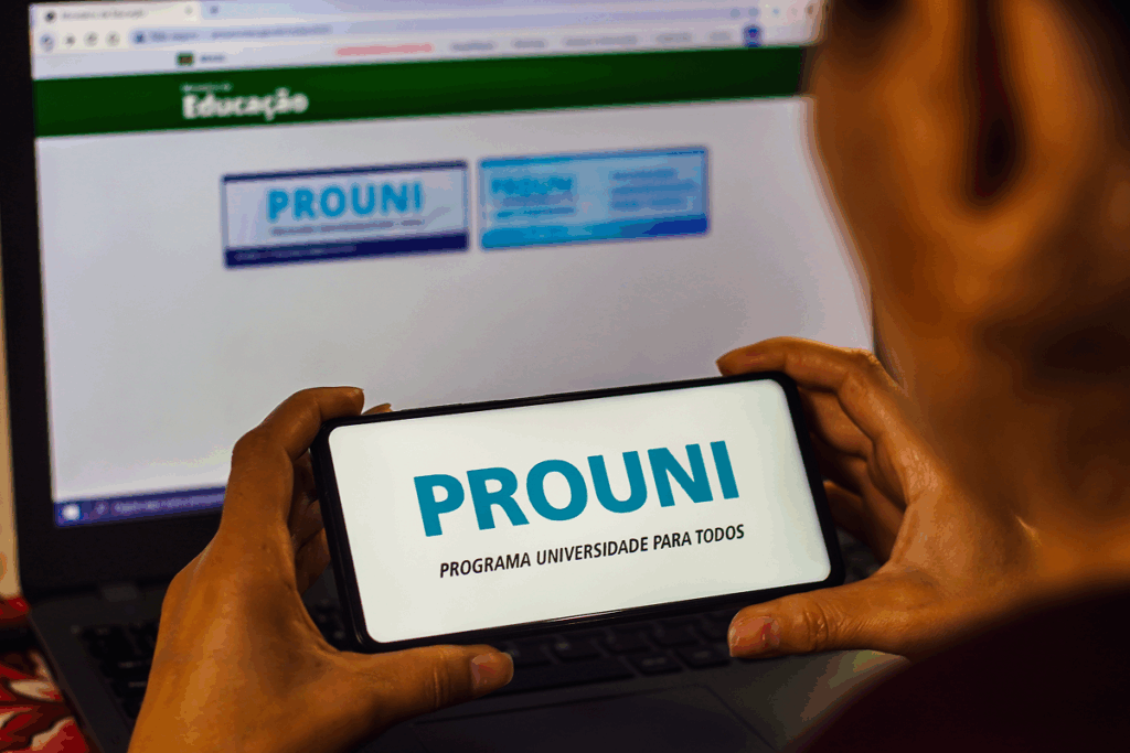 Pessoa usando o celular para acessar informações sobre o Prouni. Como usar a nota do Enem.
